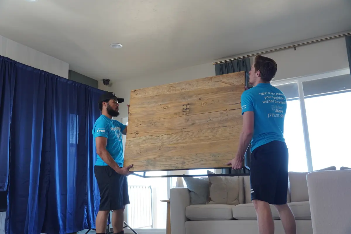 Professional movers carefully lifting office furniture
