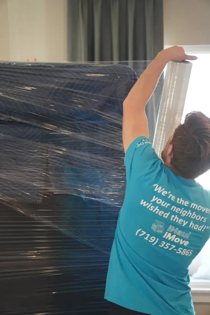 Professional mover wrapping furniture with protective padding